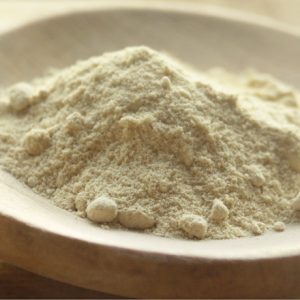 A close-up of a mound of fine, white powder, possibly flour or another type of ground ingredient, on a wooden spoon.