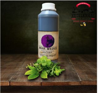 A bottle of 'Jagse Meisie' herb liqueur sits on a wooden surface with a bunch of fresh green herbs in front of it. In the background, there's a dark textured backdrop with a logo reading 'Authentic Ketelkraal Distillery Brewery Braai-Supply Store'.