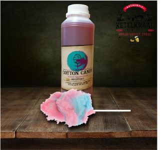 A bottle labeled "COTTON CANDY Premium Signature Essence GIN EXTRACT" with an illustration of cotton candy on the label, placed on a wooden surface beside an actual fluff of pink and blue cotton candy on a stick. In the background, there is a logo with the words "AUTHENTIC KETELKRAAL DISTILLERY, BREWERY, BRAAI-SUPPLY STORE" on a dark wall.